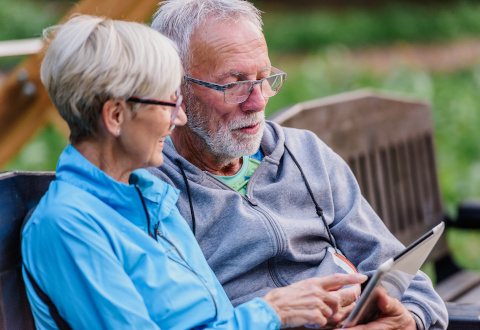 Older adult couple smiling and looking at a tablet device